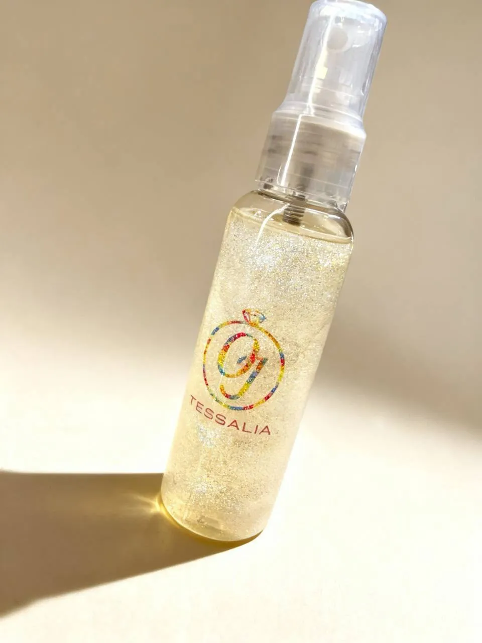 Frasco de body splash Tessalia com efeito furta-cor e a marca da Oficina das Joias