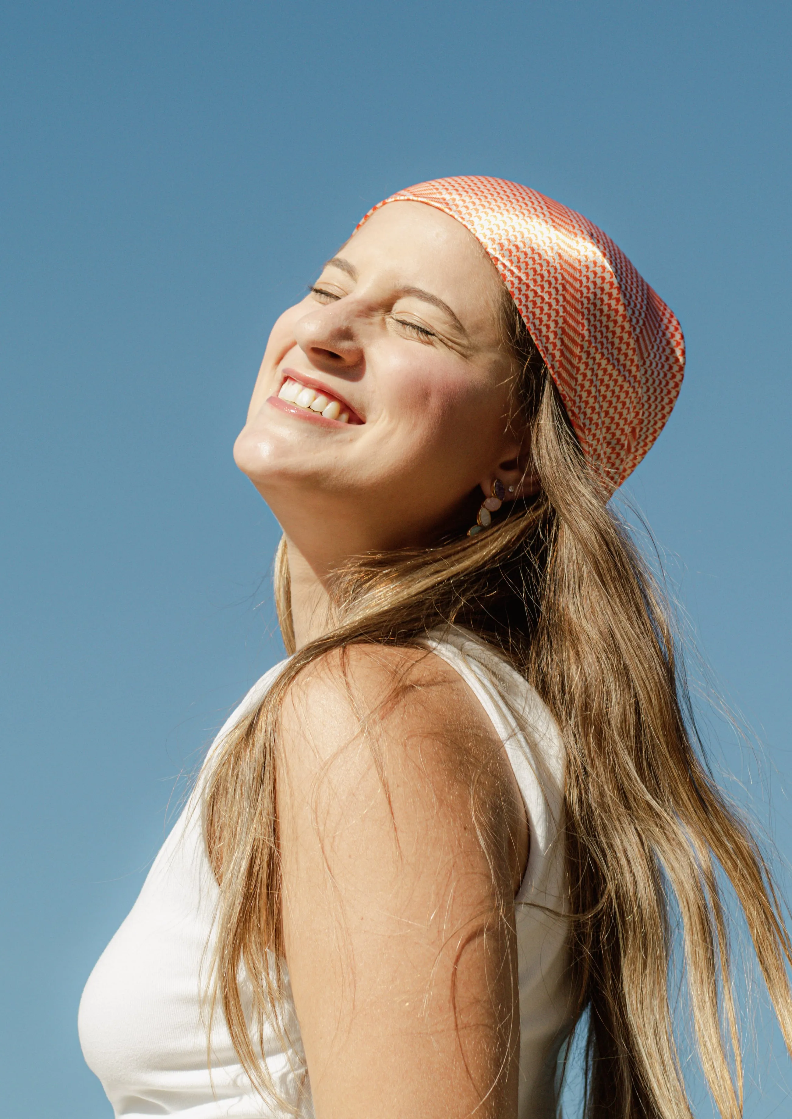 Modelo sorrindo ao ar livre, usando peças da coleção Tessalia da Oficina das Joias