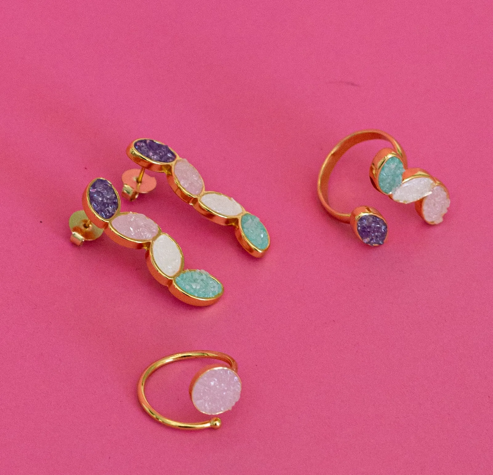 Anéis com pedras rosa e roxa sobre fundo rosa