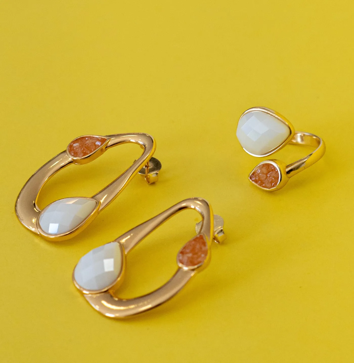 Brincos e anel com pérolas, still sobre fundo amarelo