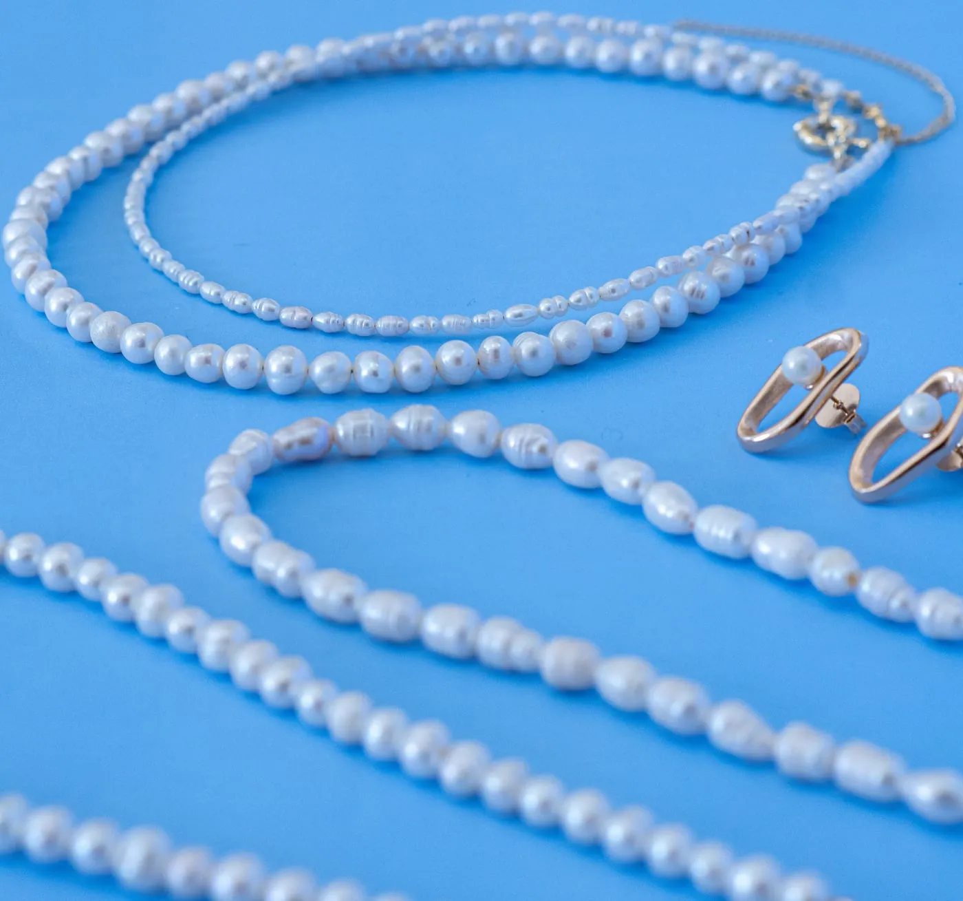 Colar de pérolas e anéis, still sobre fundo azul