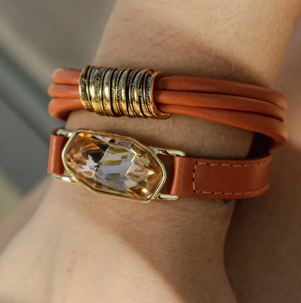 Pulseira de couro com fecho dourado no pulso